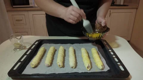 Hands brushing egg wash onto rolled pastry logs Vidéo 342362612