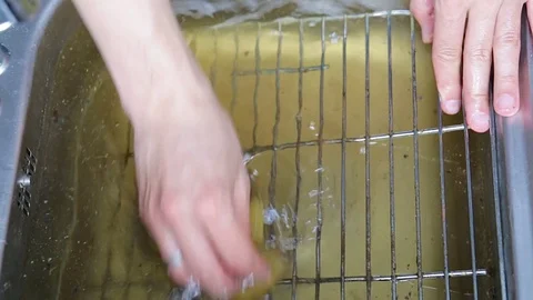 Hands brushing of the surface of a filthy grill rack in kitchen sink. Stock Footage 74893649