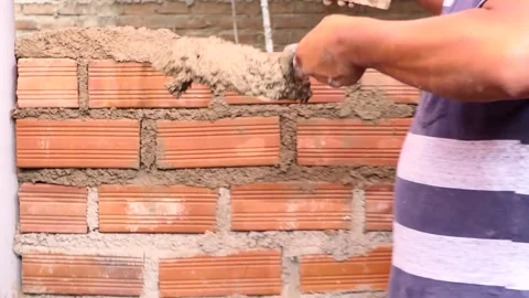 Hands build a brick wall, using a mixture of cement and wet sand. Video stock 153449597