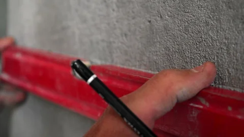The hands of a builder are close ups that measure and draw a line using a level Stock Footage 99026351