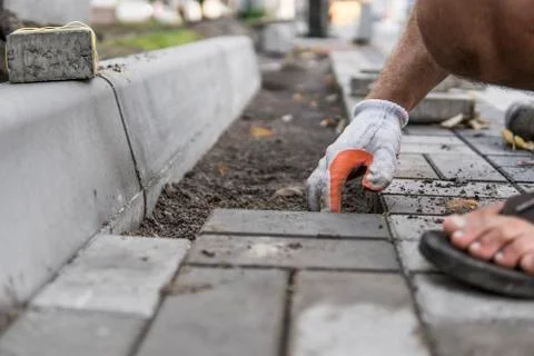 Hands of a builder in his orange gloved hands with a hammer fitting laying new Stock Photos