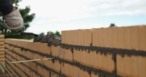 Hands of builder in white construction gloves lay bricks in fresh brickwork Stock Footage 118295661