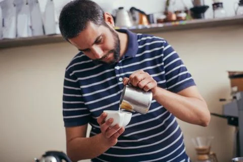 Hands of cafeteria worker making late. The man is holding a cup and pouring m Stock Photos