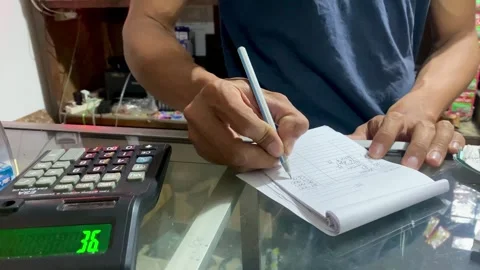 Hands Calculating Prices with Calculator and Writing Notes Stock Footage 325527809