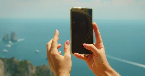 Hands capturing Capri island and Faraglioni rocks seascape with a smartphone on Video stock 327613978