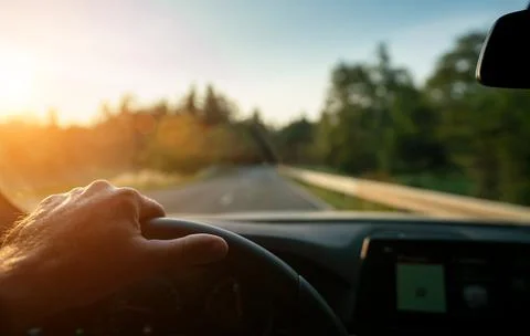 Hands of car driver on steering wheel, road trip, driving on highway road Stock Photos