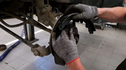 The hands of a car mechanic install the rear brake pads on a car Stock Footage 310860049