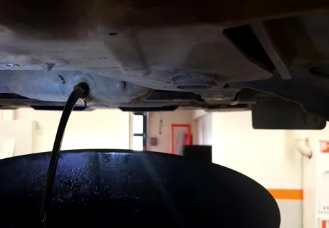 The hands of a car mechanic unscrew the drain plug and drain the oil in a car Stock Footage 310860053