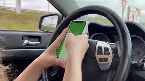 Hands in a car with a phone, the driver behind the wheel holds a smartphone.. Stock Footage 252380034