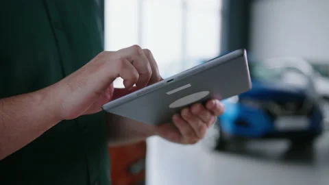 Hands of a car sales manager with a tablet, background of a modern showroom Stock Footage 240077592