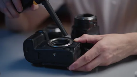 Hands carefully cleaning professional digital slr camera body with air blower Stock Footage 318518007