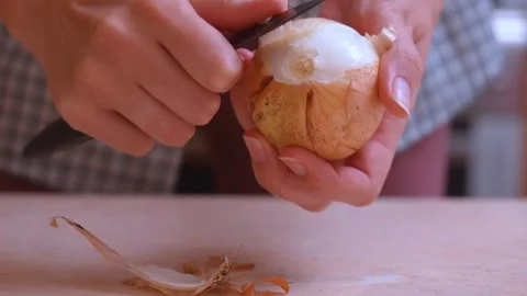 Hands carefully peel outer layers of onion with small knife on chopping surface Stock Footage 328494782