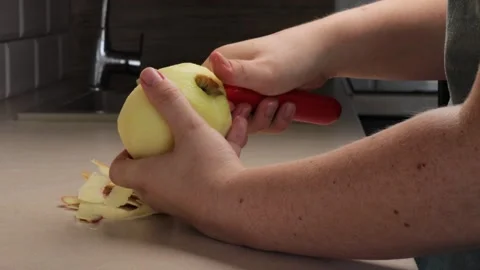 Hands carefully peeling apple with kitchen tool, apple freshness reflecting.. Stock Footage 320955863