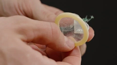 Hands Carefully Removing a Condom from Its Packaging, Highlighting Preparation Vidéo 301021883