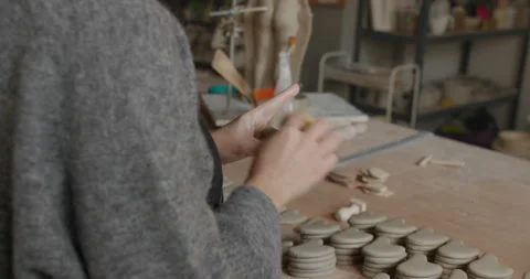 Hands carefully shaping and refining handmade ceramic pieces in a pottery studio Stock Footage 302554168