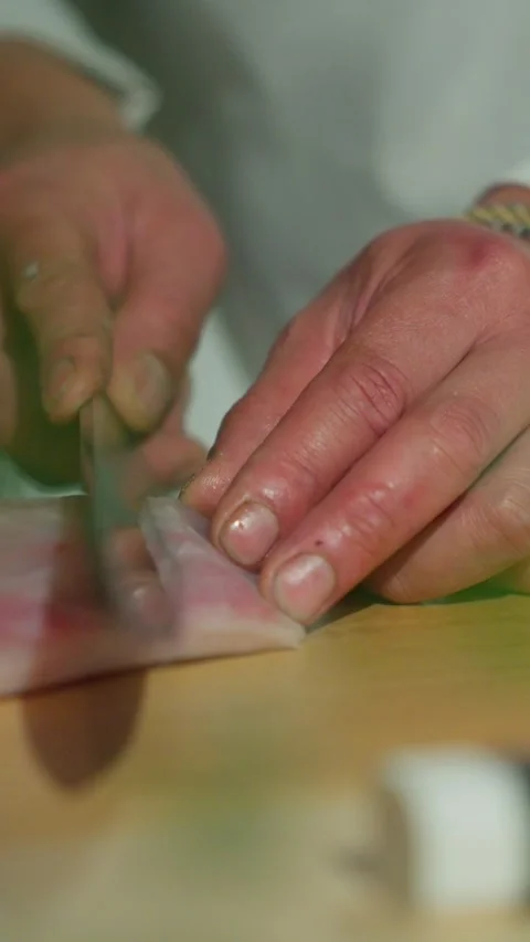 Hands Carefully Slice a Piece of Raw Fish on a Cutting Board During Food Stock Footage 328268383
