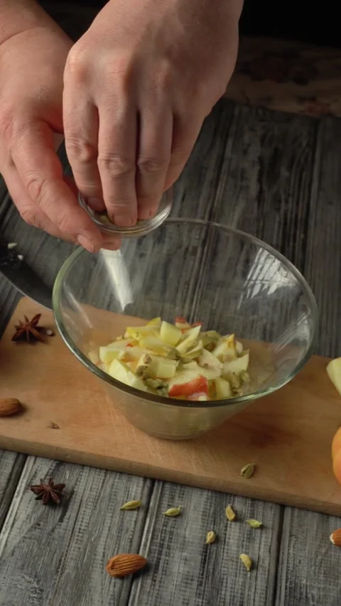 Hands carefully sprinkle spices from a small bowl into a glass bowl containing Stock Footage 331206600