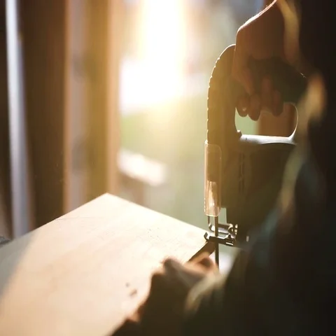 Hands of carpenter with circular saw cutting piece of wood. sun flare on Stock Footage 69539883