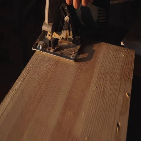 Hands of carpenter with circular saw cutting piece of wood. sun flare on Stock Footage 69540275