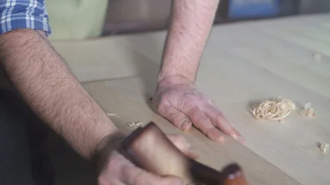 Hands of a carpenter in a shirt in a workshop with a plane at work Stock Footage 98485603