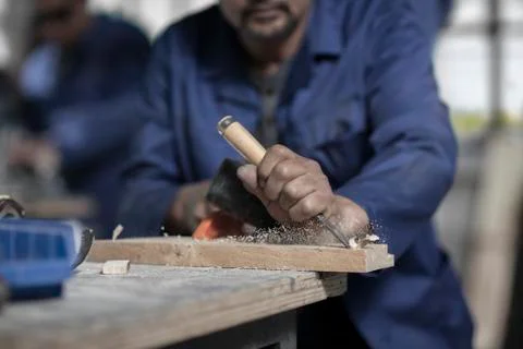 Hands of carpenter using chisel on wood in workshop Foto stock