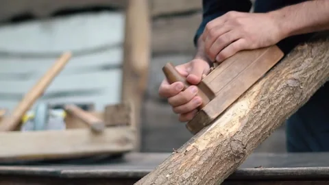 The hands of a carpenter who cut a log with a plane. The hard work of a handy Stock Footage 147330282