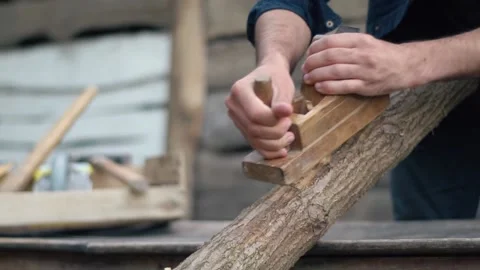 The hands of a carpenter who cut a log with a plane. The hard work of a handy Stock Footage 147330924