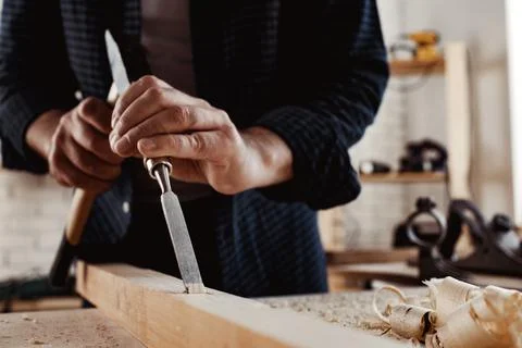 Hands of a carpenter working with chisel and hammer Stock Photos