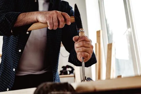 Hands of a carpenter working with chisel and hammer Stock Photos