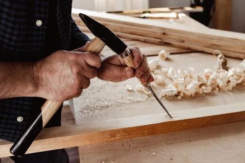 Hands of a carpenter working with chisel and hammer Stock Photos