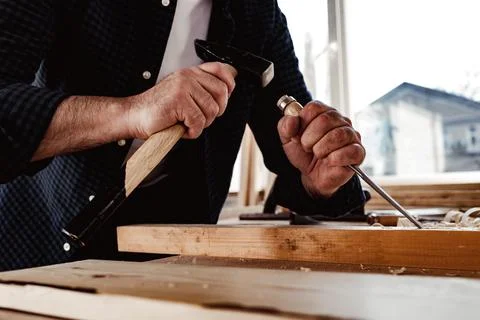 Hands of a carpenter working with chisel and hammer Stock Photos