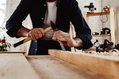 Hands of a carpenter working with chisel and hammer Stock Photos