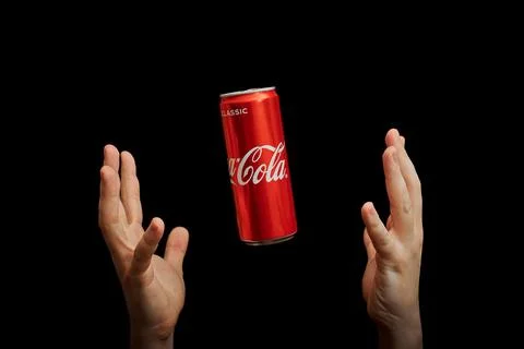 Hands catch Coca Cola can, black background Stock Photos