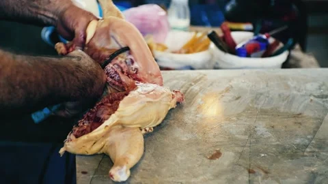 Hands of a caucasian man cutting chicken in the market. Cutting raw chicken into Video stock 213570879
