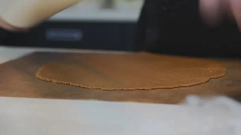 The hands of a Caucasian pastry chef roll the dough with a white rolling pin Stock Footage 152849513