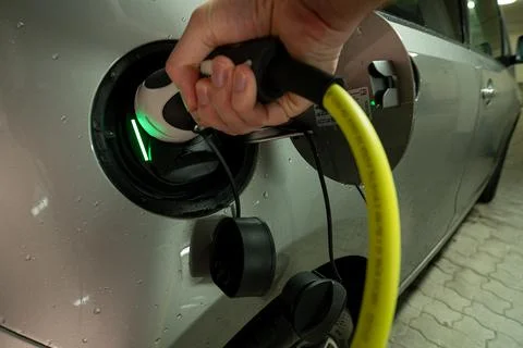 Hands on the charging wire of an e-car with an active charging process, shown by Stock Photos