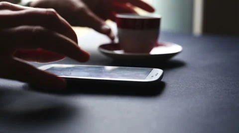 Hands chatting with smartphone and drinking coffee, indoor for breakfast Stock-Footage 56450961