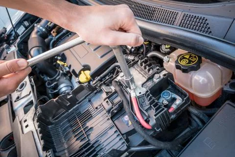 Hands checking the bolt of a car battery with a wrench Stock Photos