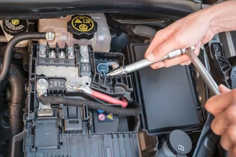 Hands checking the bolt of a car battery with a wrench Stock Photos
