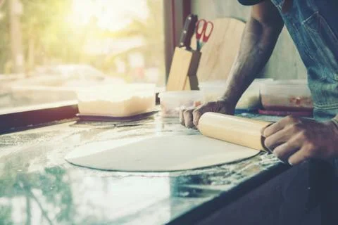 Hands chef baking dough with rolling pin on marble table Foto stock