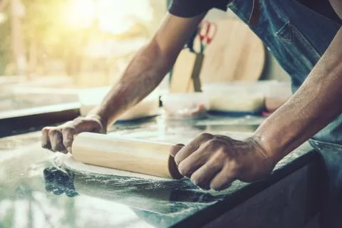 Hands chef baking dough with rolling pin on marble table Foto stock