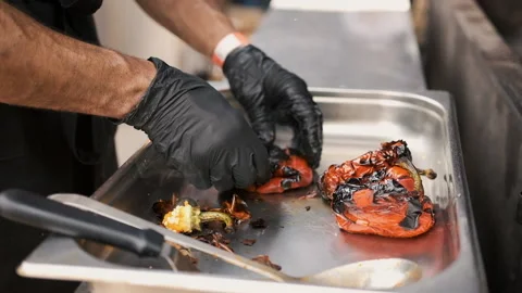 Hands of chef in black mittens close up preparing grilled peppers Stock Footage 194042527