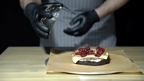 Hands of the chef cooking a black burger with smoked bacon and cherry sauce. Stock Footage 113611213