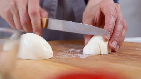 The hands of the chef cut slices of mozzarella cheese with a knife  Stock Footage 154368762
