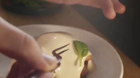 The hands of the chef gently add fresh watercress leaves to the benedict Video stock 150963986