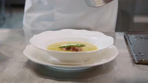 Hands of chef holding spoon in hands, adding asparagus into soup. Kitchen of Stock Footage 205198078