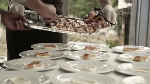 Hands of chef put freshly cooked salmon into plates, close up view Vidéo 229832021