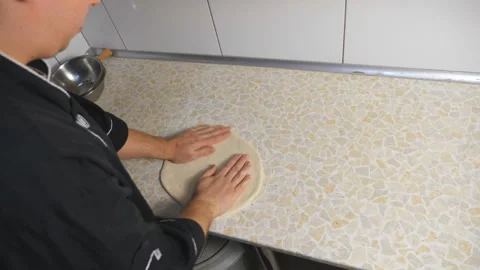 Hands of chef shaping floured dough for pizza on a kitchen table at cuisine Stock Footage 146649629