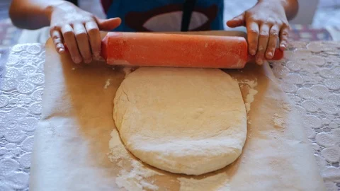 The hands of the chefs roll the raw dough with a rolling pin on the table Stock Footage 95803070