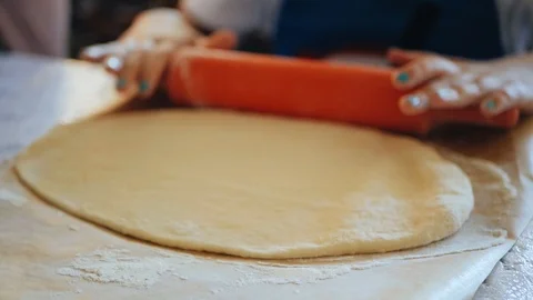 The hands of the chefs roll the raw dough with a rolling pin on the table Stock Footage 95803092